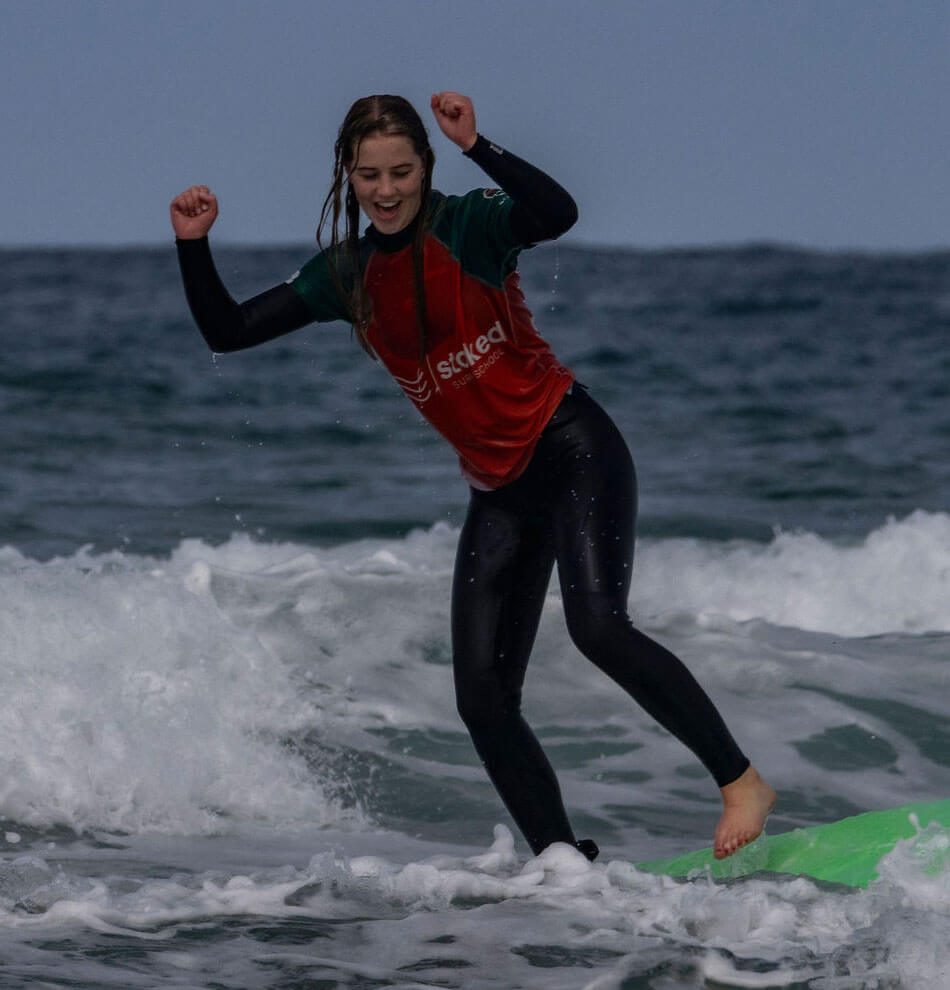 A happy surfer on surf hire gear from Stoked Surf School