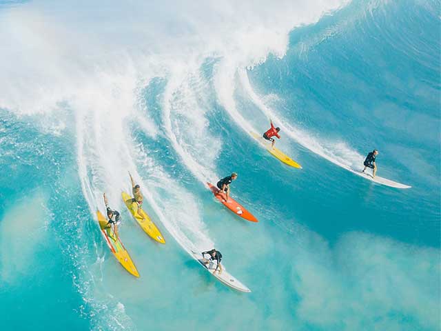 A group of big wave surfers, riding gun surfboards