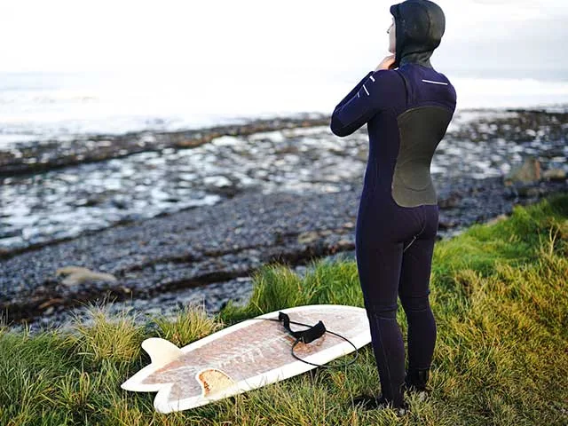 A woman with a fish surfboard at her feet