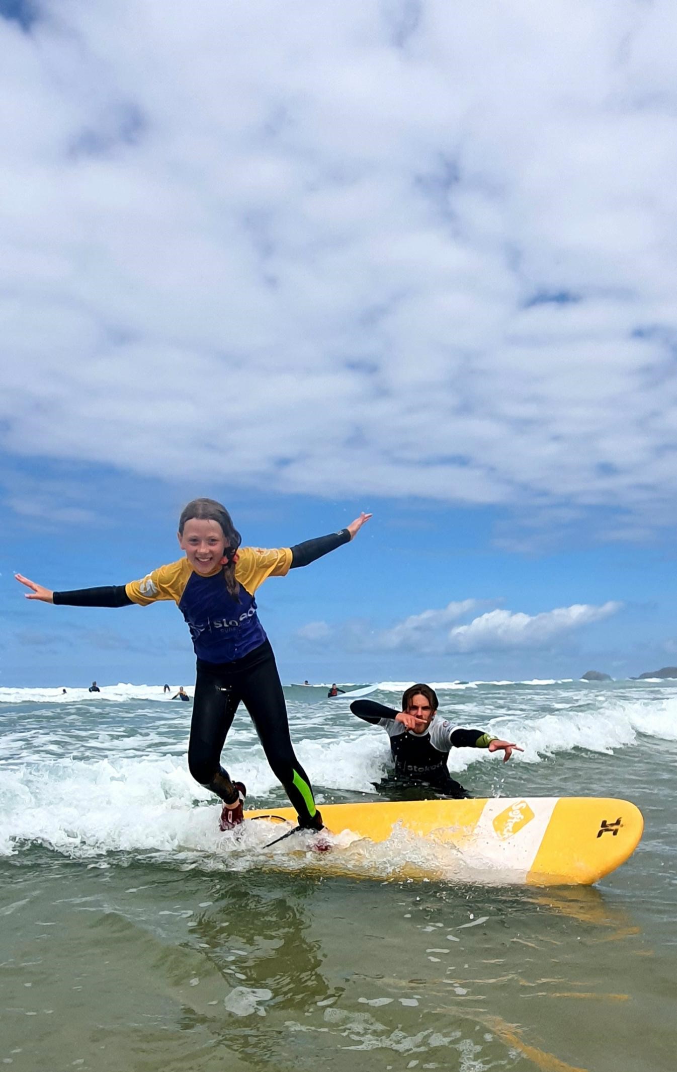 A child learning to surf with Stoked Surf School