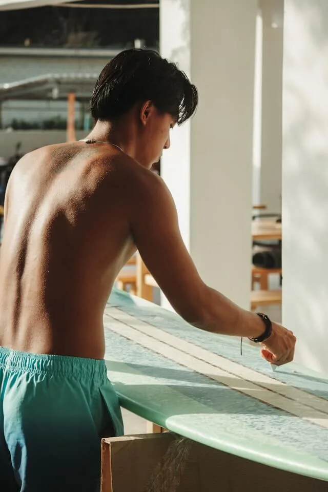 A man waxing his surfboard