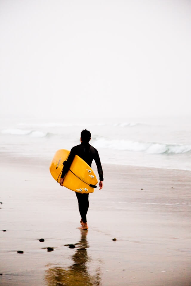 A lone surfer walking along a beach