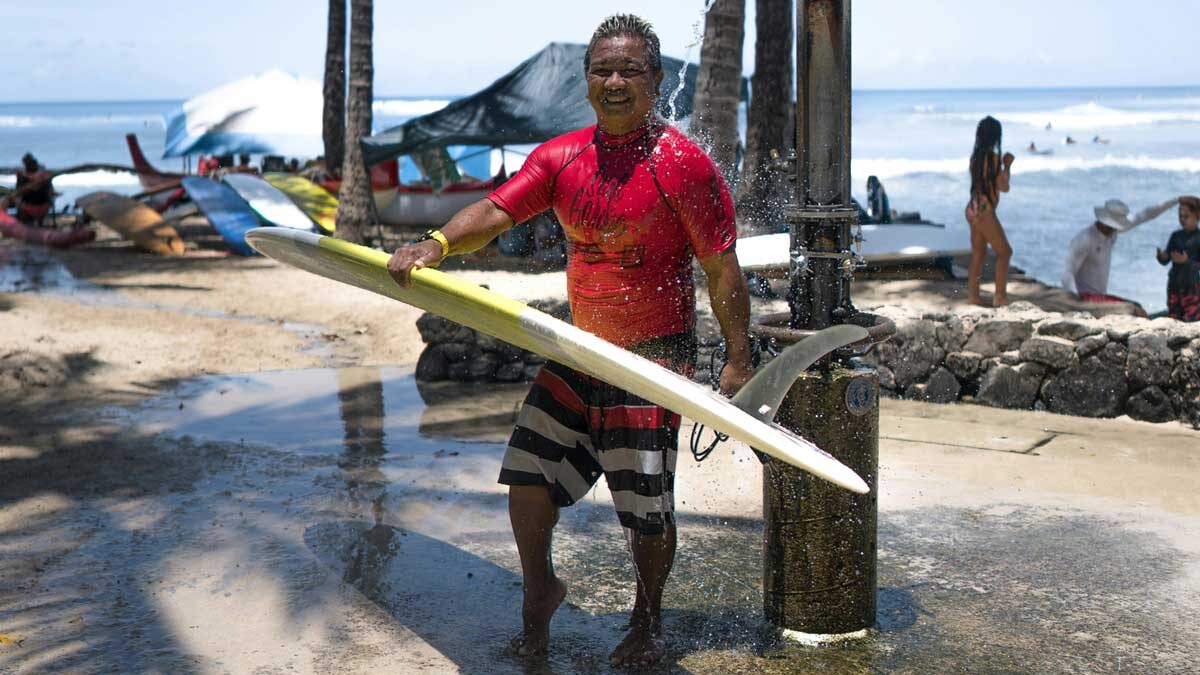 A man washing himself and his surfboard