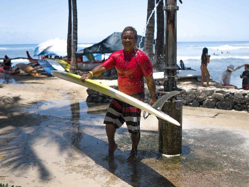 A man washing himself and his surfboard