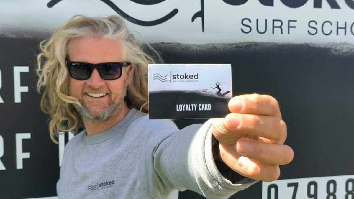 Head coach Julian holding the Stoked Surf School loyalty card