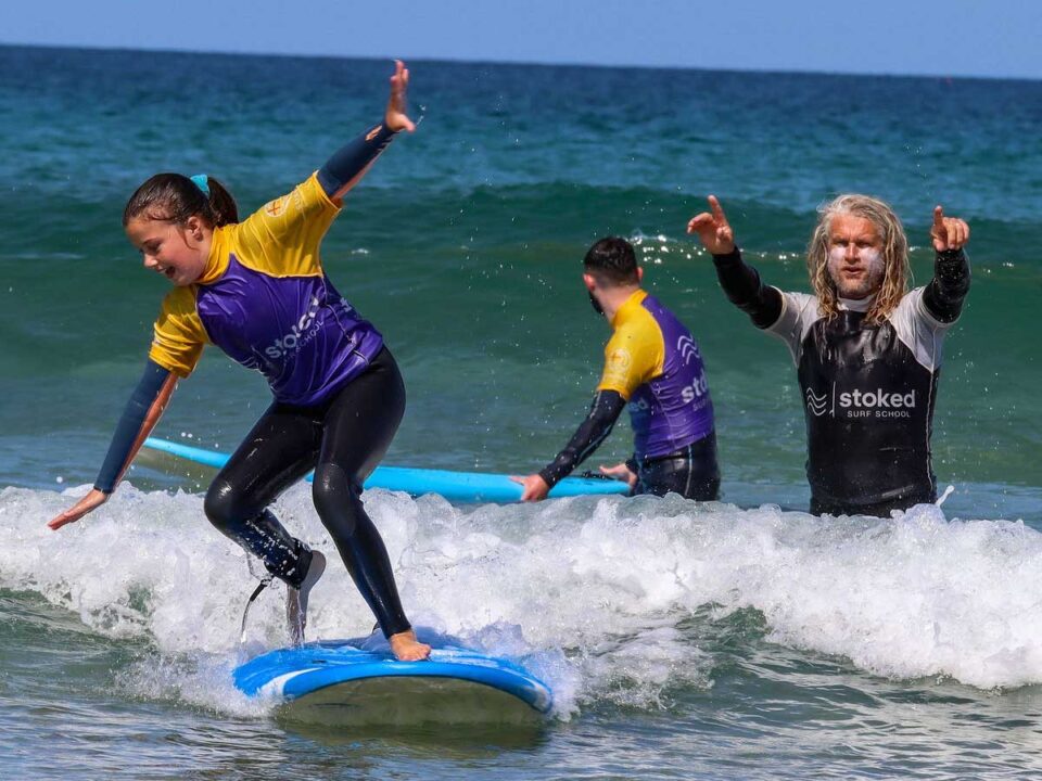 A surfer taking a lesson with Stoked Surf School during Tunes in the Dunes