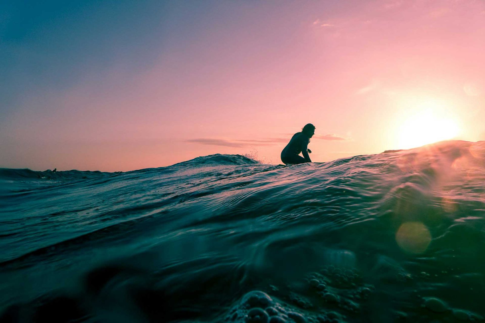 A sillouhette of a surfer at sunset