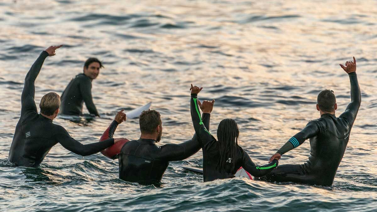 A line of happy surfers in the water