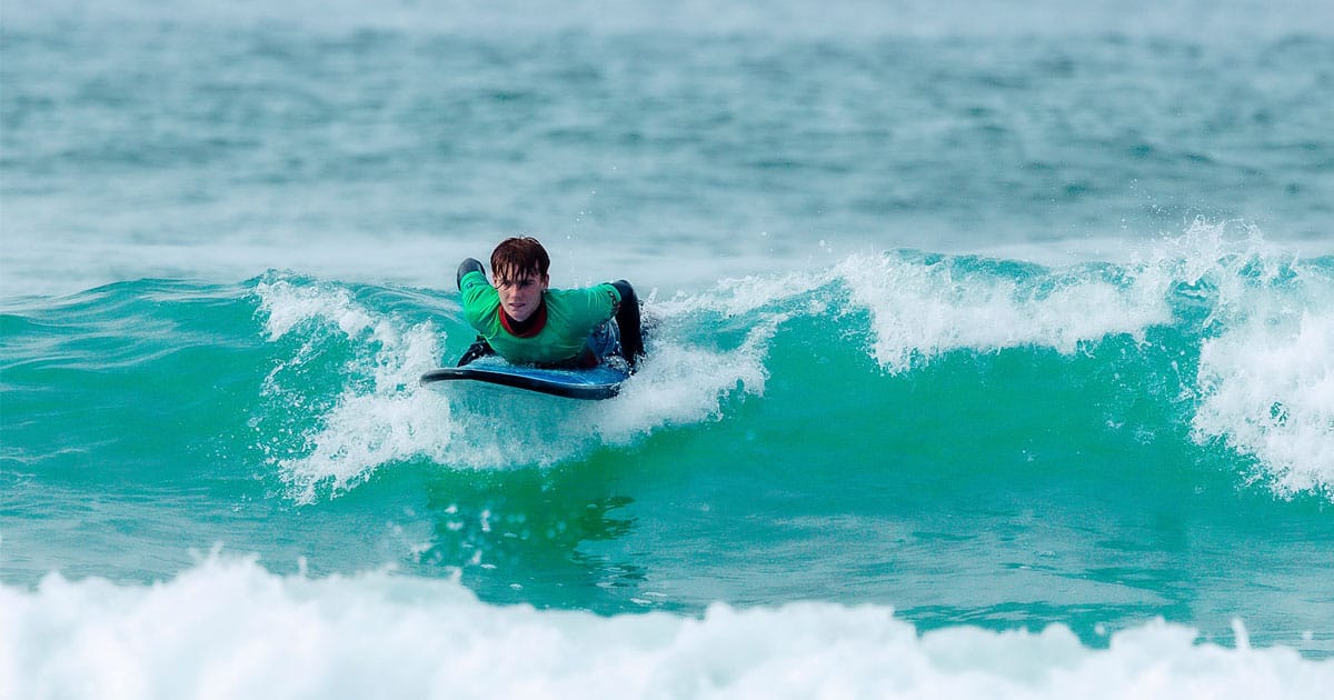A surfer riding a wave after hiring a surfboard and a wetsuit