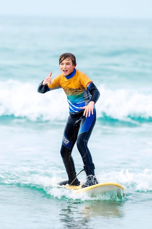 A happy young surfer smiling and giving a thumbs-up