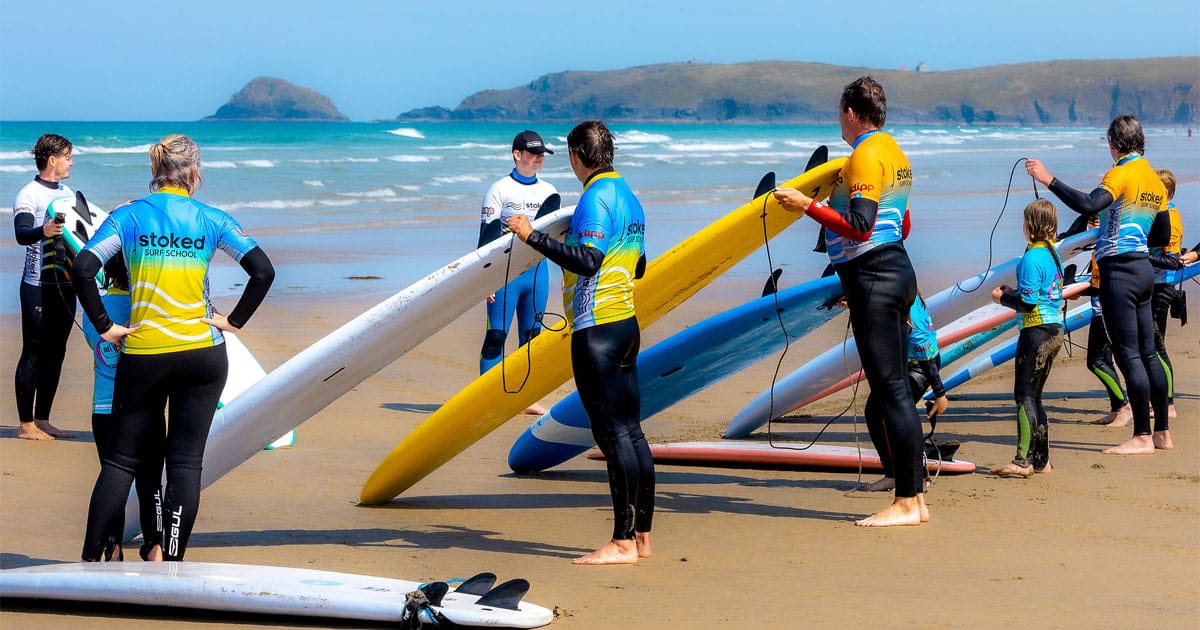A large group having a surf lesson with Stoked Surf School on Perranporth Beach