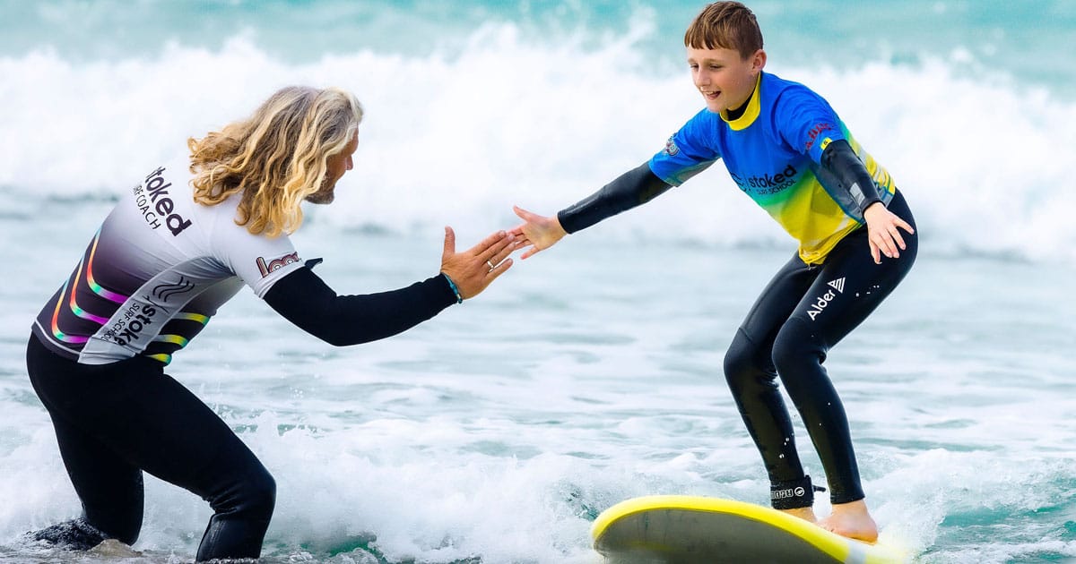 Head coach Julian high-fiving a teenaged boy having a private surf lesson