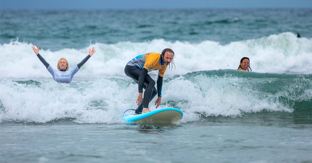 A man surfing on a wave having a surf lesson