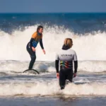 Easter 2026 Offers and more at Stoked Surf School 5 A woman riding a wave on Perranporth Beach with Stoked Surf School