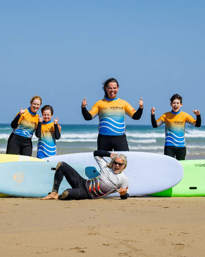 A family who have learned to surf, posing with head coach Ju at Stoked Surf School