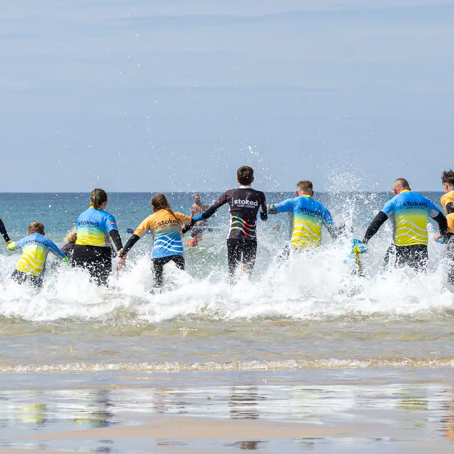 A large group heading into the sea for a surf lesson