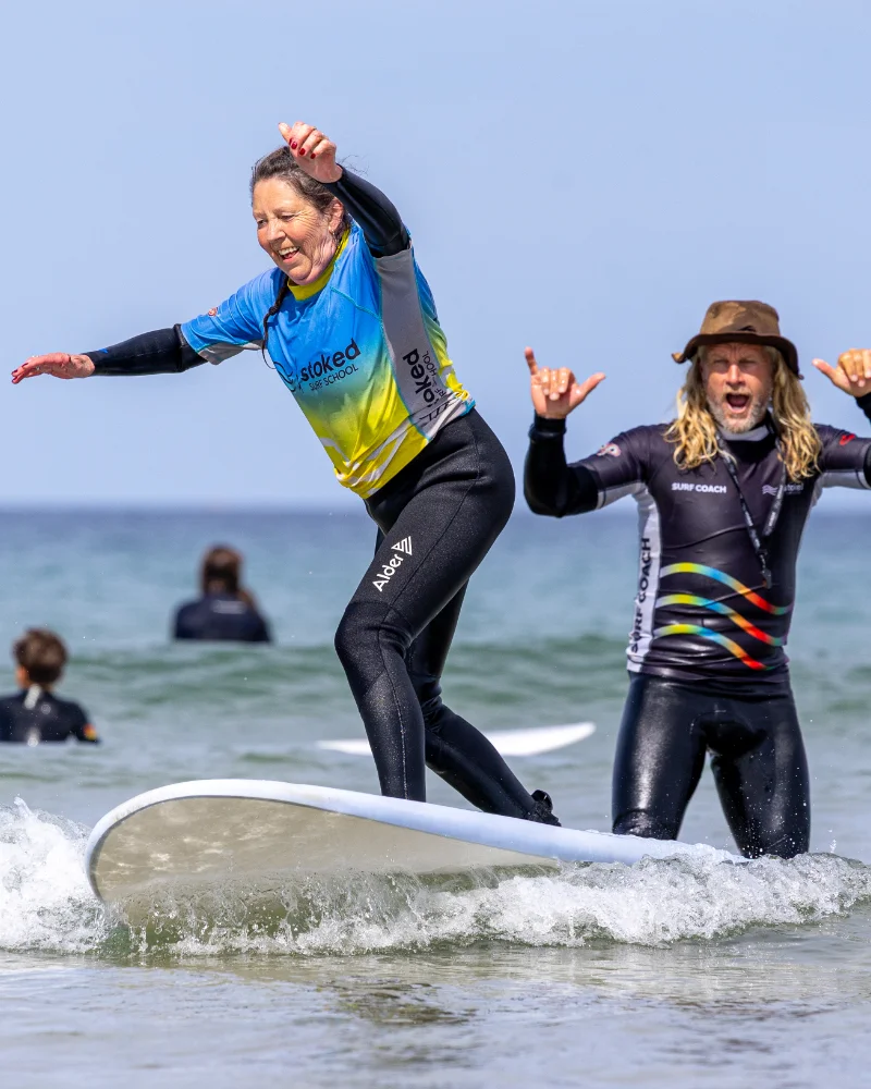 A woman riding on a surf board in the sea at Perranporth