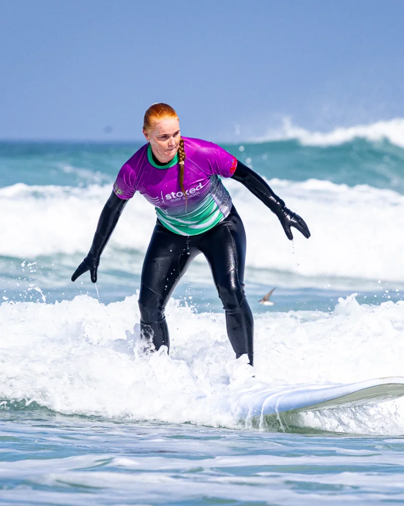 A surfer riding a wave on Perranporth beach