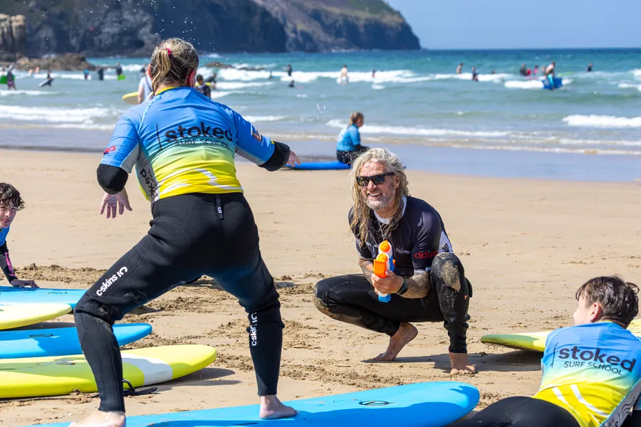 Surf coach demonstrating the pop-up on the sand while a beginners group watches