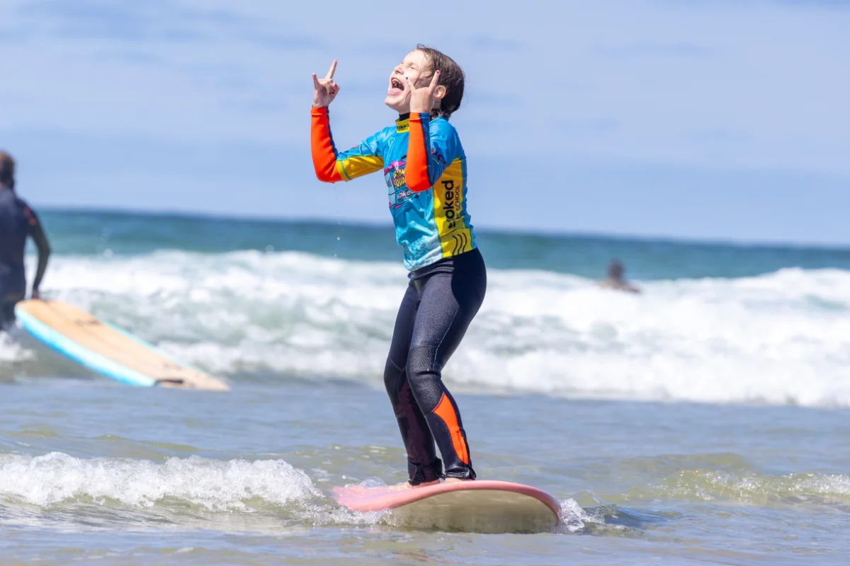 A young surfer celebrating after catching a wave at Perranporth